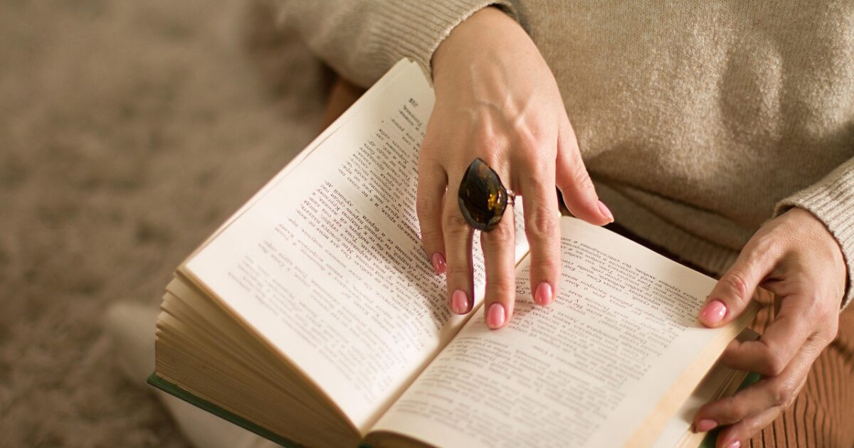 膝の上で本を読む女性の手元のクローズアップ