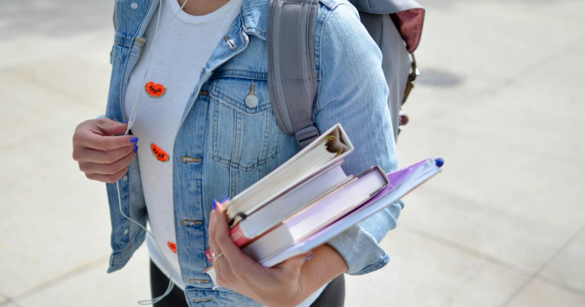 教科書とノートを持つ学生の上半身とバックパック