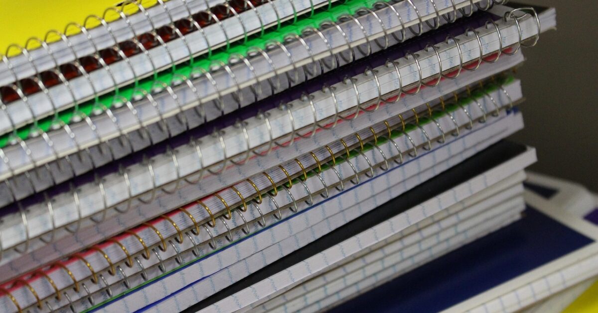 カラフルなリングノートが重ねられた文具の山
